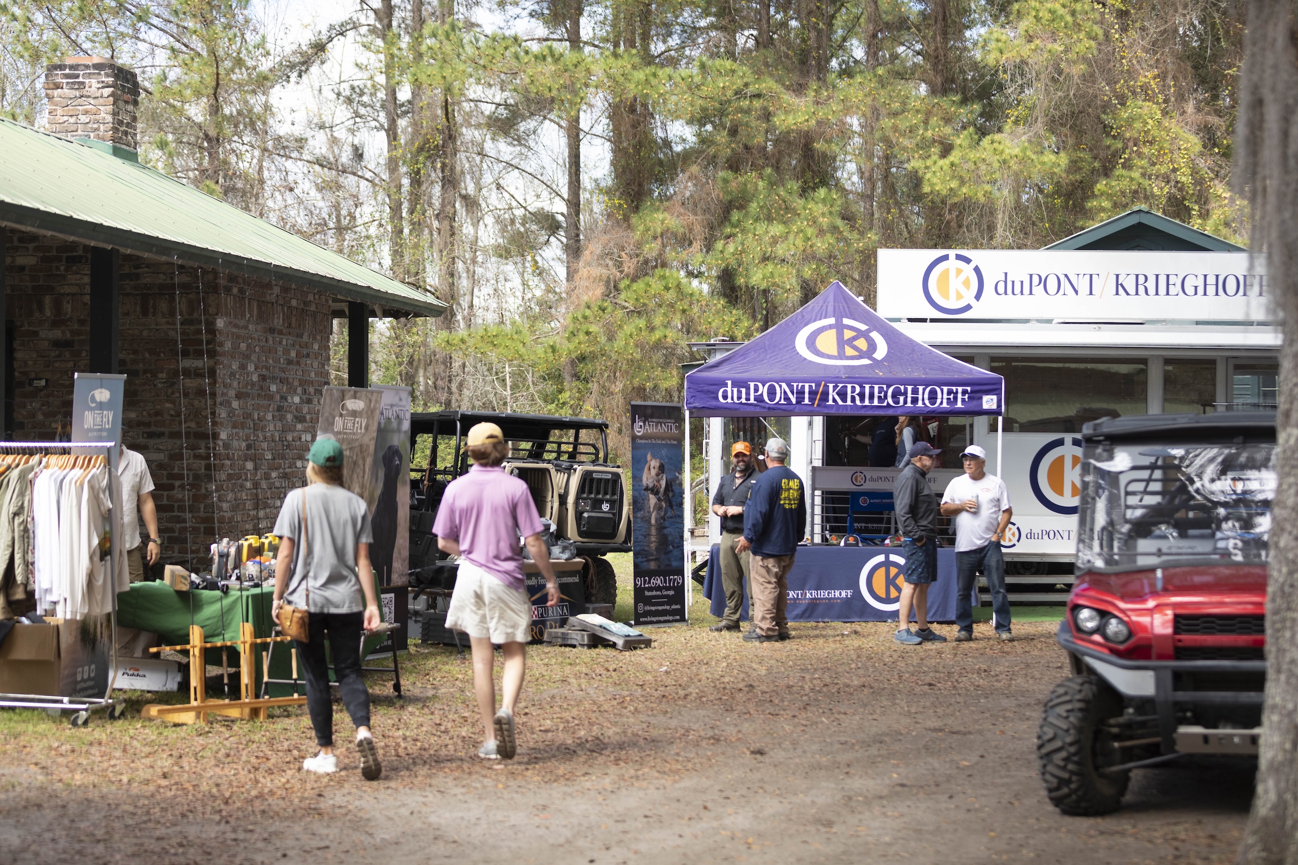 A few people walk along the outdoor vendor area of the Seminole Cup on a sunny day.